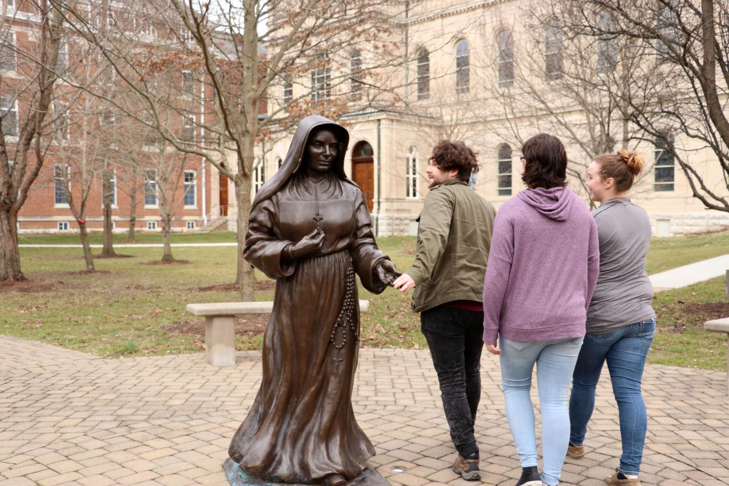 当学生们走过雕像时，他们会触摸圣母西奥多·盖林的手.